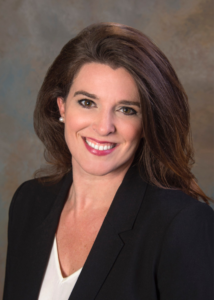 Image of Amanda Tuite wearing a black suit jacket and white shirt smiling at the camera.