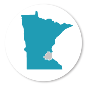 Image of MN State outline on a white background with a gray circle. The seven county metro is outlined in gray, while the remaining image is in teal. The teal color represents Greater MN; the area in which the grant serves.