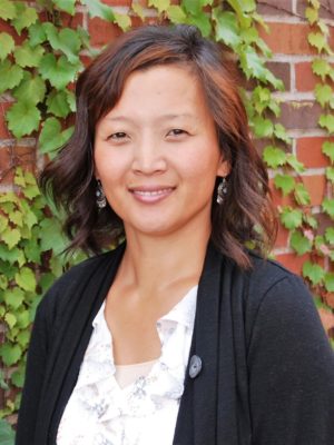 Image of Sunny Brysch standing in front of a brick wall smiling at the camera.