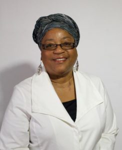 image of Lisa Weems wearing a head wrap, glasses, and dangly earrings, smiling at the camera with a white background