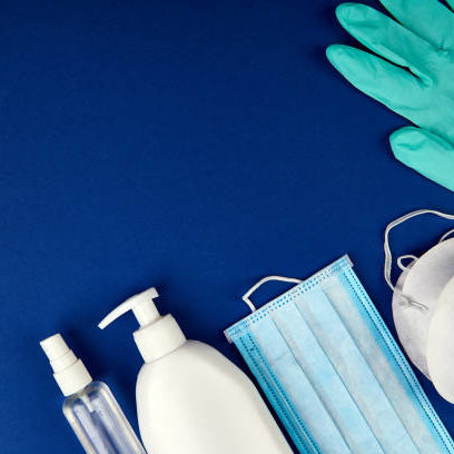 Flat lay of Coronavirus protection, medical protective masks, gloves, hand sanitizer bottles, antiseptic, disinfection, spray on blue background, copy space.